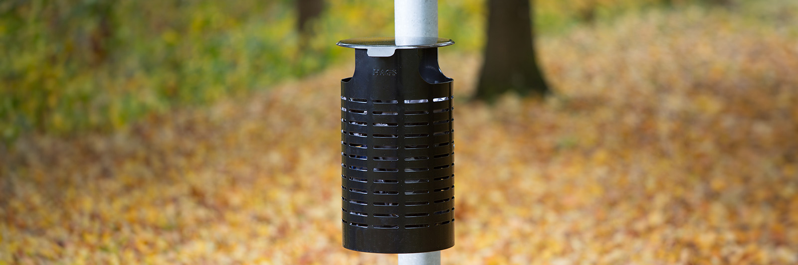 Black litter bin mounted on a lighting pole in the streets.